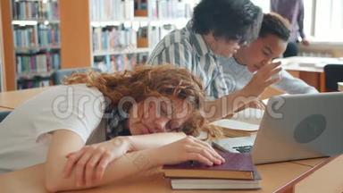 一个漂亮的女孩<strong>睡</strong>在图书馆的桌子上，而其他<strong>学生</strong>在<strong>学习</strong>交谈